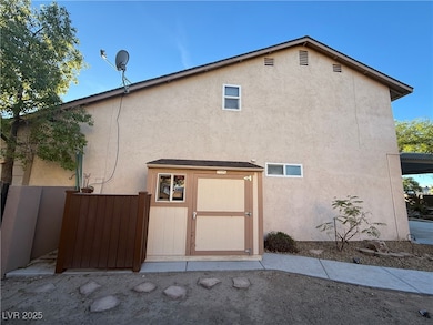 side view of house featuring stucco siding and a storage shed