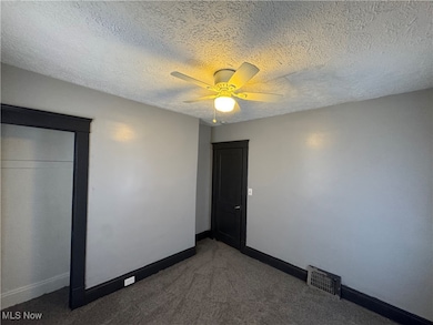 Unfurnished bedroom with a textured ceiling, carpet floors, and a ceiling fan