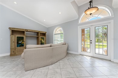 Living room has tiled flooring laid on the diagonal, high ceiling, and crown moulding.