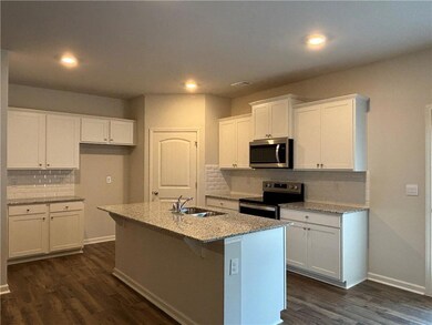 Kitchen featuring appliances with stainless steel finishes, white cabinetry, backsplash, dark wood finished floors, and recessed lighting