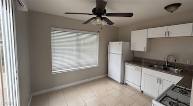 Kitchen with ceiling fan, white appliances, white cabinetry, and light tile patterned floors