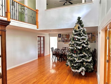 Family area featuring a high ceiling, a ceiling fan, wood finished floors, and baseboards