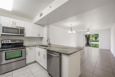Kitchen featuring stainless steel appliances, a textured ceiling, backsplash, light tile patterned floors, and a peninsula