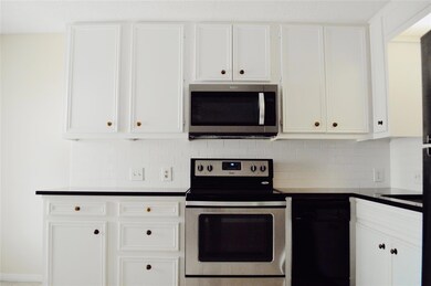 Kitchen with dark countertops, white cabinetry, a