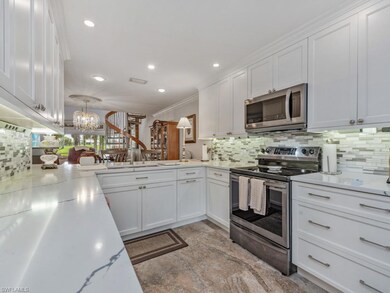 Kitchen with white cabinetry, stainless steel appliances, backsplash, recessed lighting, and a chandelier