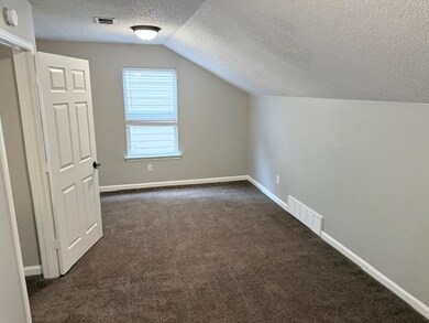 Bonus room with dark colored carpet, visible vents