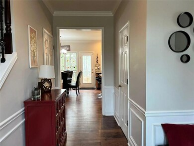 Hallway featuring crown molding, dark wood-type flooring, wainscoting, and a decorative wall