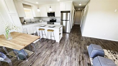 Kitchen with stainless steel appliances, a sink, a kitchen island, and white cabinets