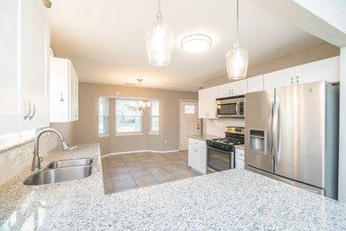 An alternate view of the kitchen highlights the recently replaced stainless appliances that include a built in microwave, four burner Amana gas cooktop, gas oven, dishwasher, and even includes the LG French Door refrigerator.