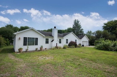 Front view of property with a chimney, a lawn, and a garage