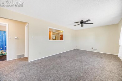 Empty room with ceiling fan, carpet flooring, a textured ceiling, and baseboards