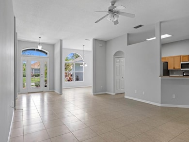 Unfurnished living room with light tile patterned flooring, a textured ceiling, a ceiling fan, and arched walkways