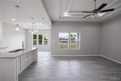 Kitchen with a raised ceiling, hanging light fixtures, ceiling fan with notable chandelier, and white cabinetry