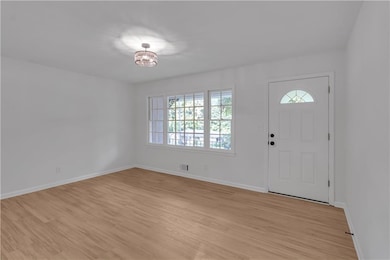 Entrance foyer featuring light wood-type flooring, baseboards, and a chandelier