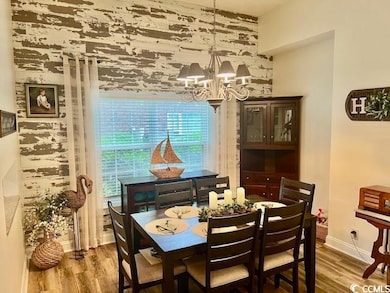 Dining room featuring wood finished floors, a chandelier, and baseboards
