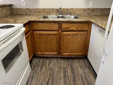 Kitchen featuring white appliances, a sink, dark w