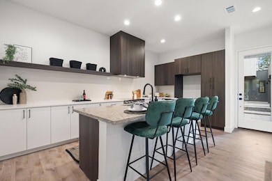 Kitchen with dark brown cabinetry, open shelves, a kitchen breakfast bar, modern cabinets, and light wood finished floors