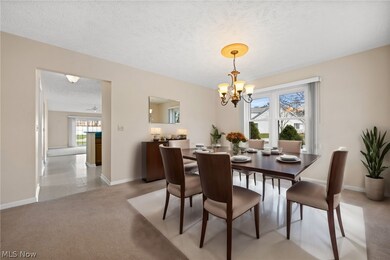 Dining area with light carpet, a textured ceiling, and a chandelier - virtually staged with furniture/decor