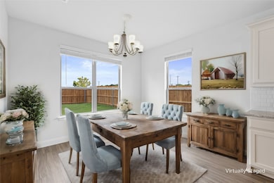 Dining area with light wood-style flooring, plenty of natural light, and a chandelier