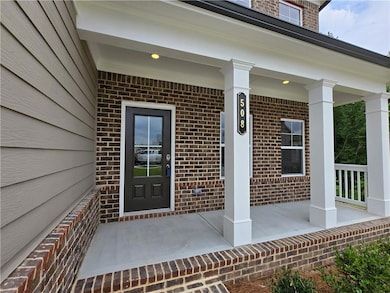 Doorway to property featuring a porch and brick siding