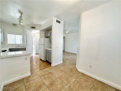 Kitchen with tile countertops, freestanding refrig