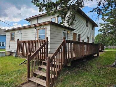 Rear view of property with a wooden deck and a law