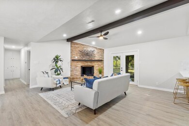 Living room featuring light wood-type flooring, a fireplace, ceiling fan, and french doors