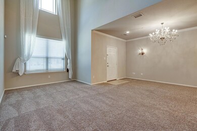 Carpeted spare room with baseboards, visible vents, crown molding, and a chandelier