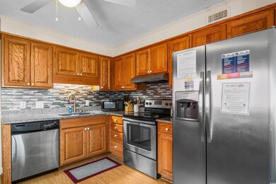 Kitchen with appliances with stainless steel finishes, a sink, under cabinet range hood, brown cabinets, and ceiling fan