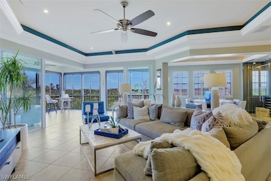 Tiled living room featuring ceiling fan, a raised ceiling, and ornamental molding