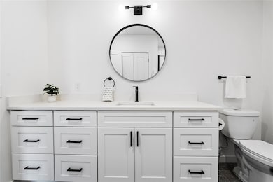 Bathroom featuring vanity, toilet, and baseboards