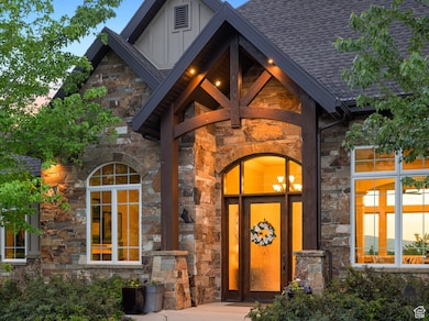 Doorway to property featuring stone siding, board and batten siding, and a shingled roof