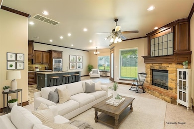 Living room with crown molding, recessed lighting, a stone fireplace, a chandelier, and ceiling fan