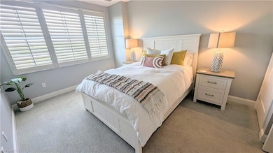 Queen guest bedroom with baseboards and light colored carpet