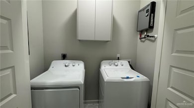 Washroom featuring water heater, washer and dryer, electric dryer hookup, and cabinets
