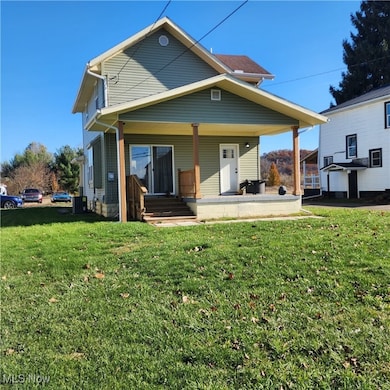 Rear view of house featuring covered porch and a lawn