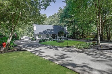 View of front of home featuring a chimney, a front lawn, asphalt driveway, and covered porch