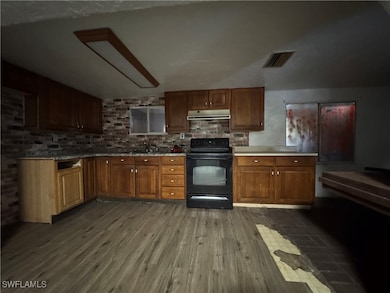 Kitchen with black electric range and wood-type flooring