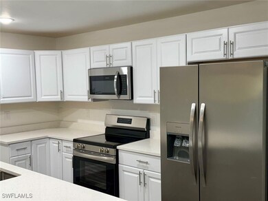 Kitchen featuring white cabinetry, light stone cou