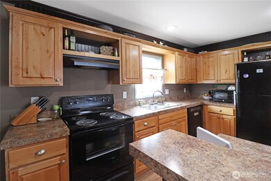 Knotty pine cabinets paired with rich, dark walls create a warm rustic feel, while black appliances and ample counter space bring function and style together in this inviting kitchen.