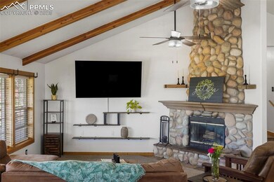 Living area with a ceiling fan, beam ceiling, a fireplace, baseboards, and high vaulted ceiling