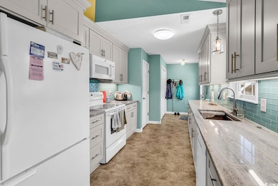 Kitchen with white appliances, a sink, backsplash,