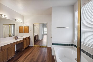 Bathroom with wood-type flooring, tiled bath, double sink, and oversized vanity