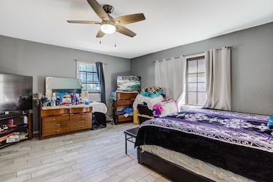 Bedroom with wood finished floors, ceiling fan, and cooling unit