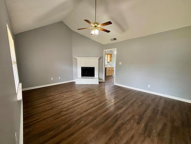 Unfurnished living room featuring a ceiling fan, lofted ceiling, dark wood-type flooring, baseboards, and a fireplace