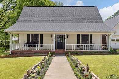 View of front of home featuring covered porch, a shingled roof, and a front yard