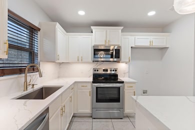 Kitchen featuring stainless steel appliances, light stone counters, backsplash, and sink