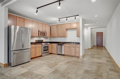 Another angle of the kitchen highlights its clean layout and functionality. The refrigerator is included with the sale. To the right, a hallway leads to the flex room, while the door at the far end provides access to the corridor connecting to the garage building.