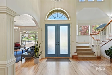 Foyer featuring a towering ceiling, a chandelier, stairs, wood finished floors, and arched walkways