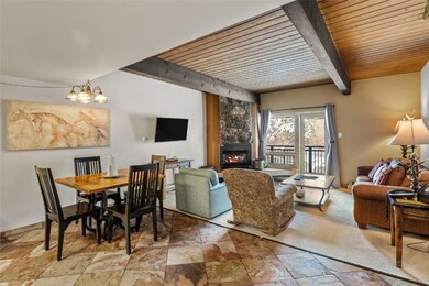Dining room featuring a fireplace, a wooden ceiling with exposed beams, and stone tile floors